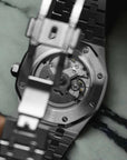 Close-up of a silver watch with a visible brand logo on a marble surface
