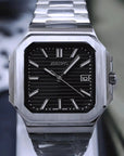 Silver watch with black face on a reflective surface