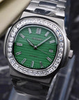 Silver watch with green face on a dark textured background