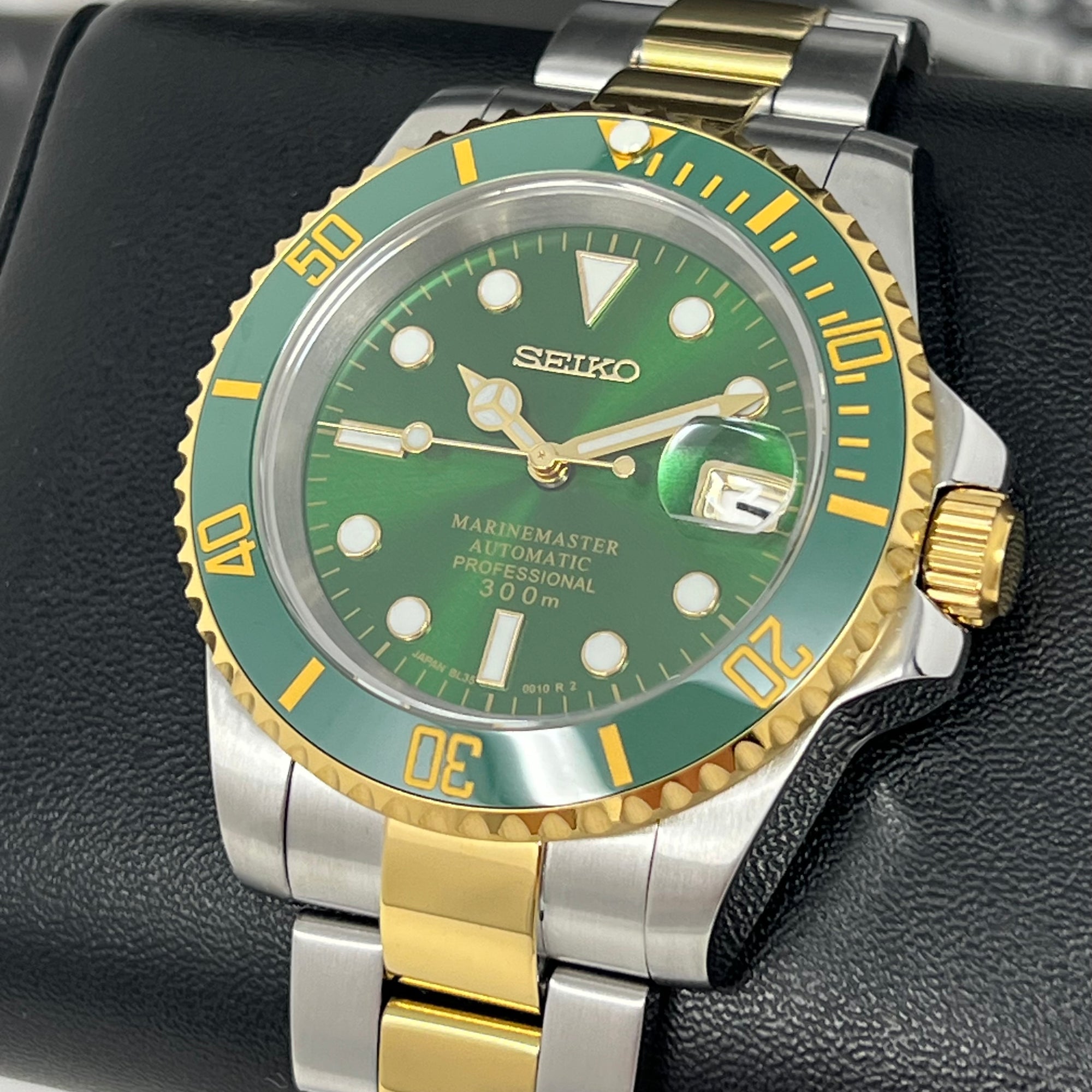 Seiko mod watch with green face and gold accents on a black background