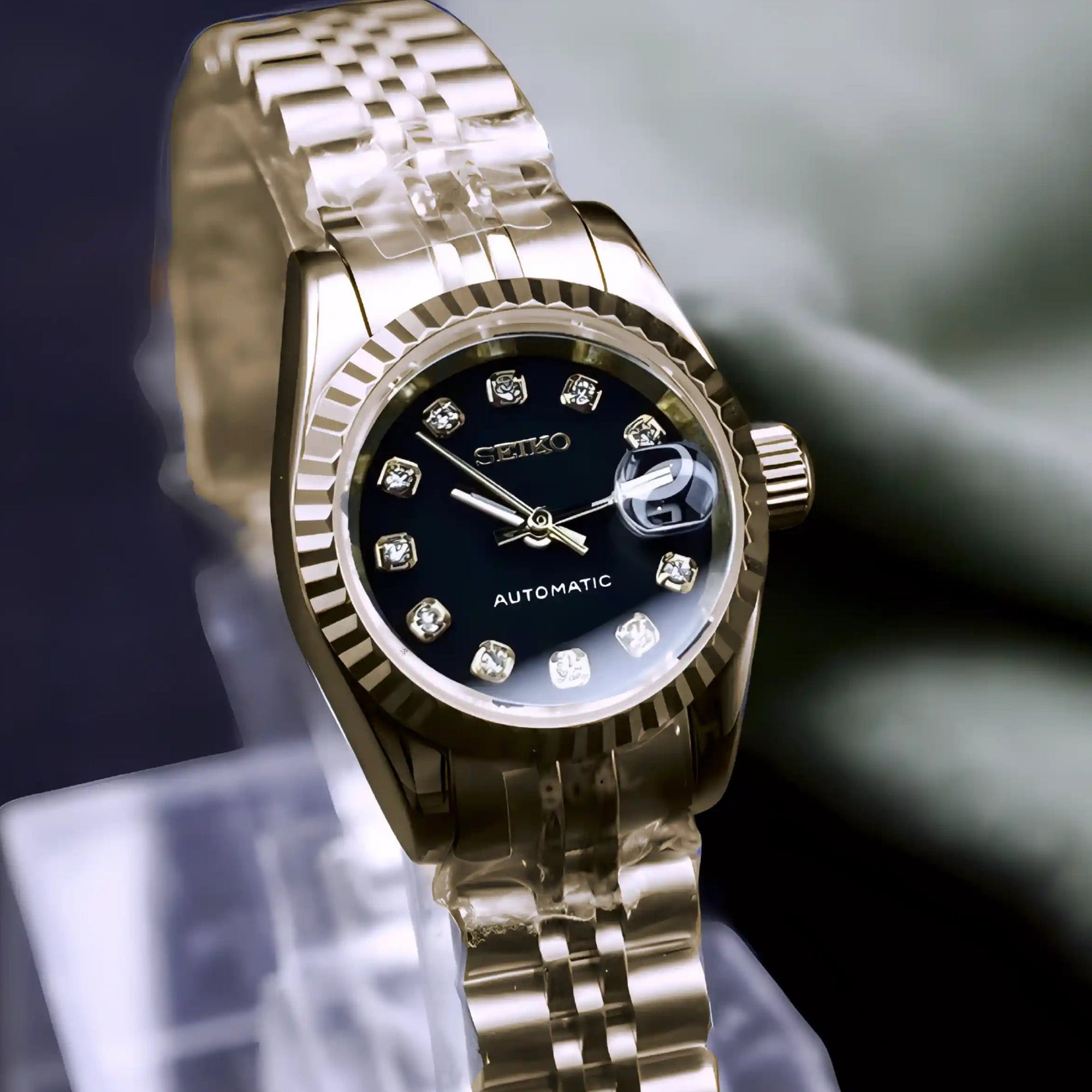 Gold wristwatch with a clear stand on a dark background