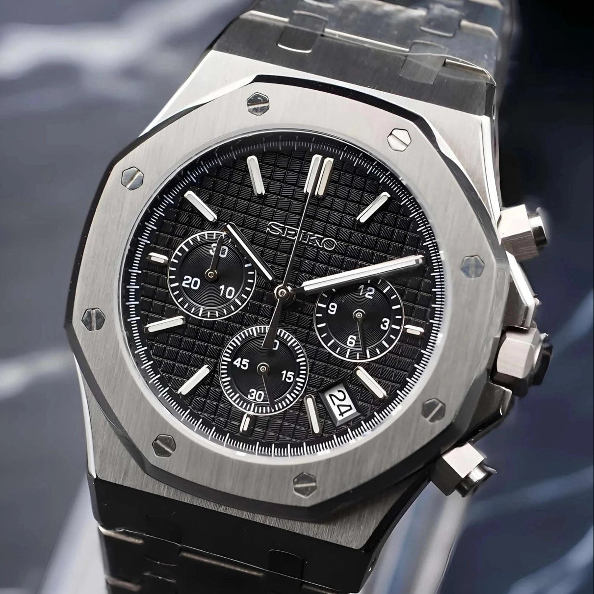 Silver watch with black face on a dark background