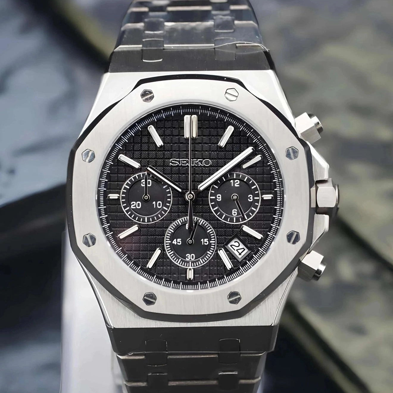 Luxury watch with black dial and silver case on a clear stand