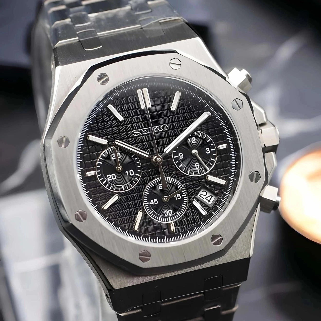 Silver and black watch with detailed face on a reflective surface