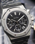 Silver and black watch with detailed face on a reflective surface