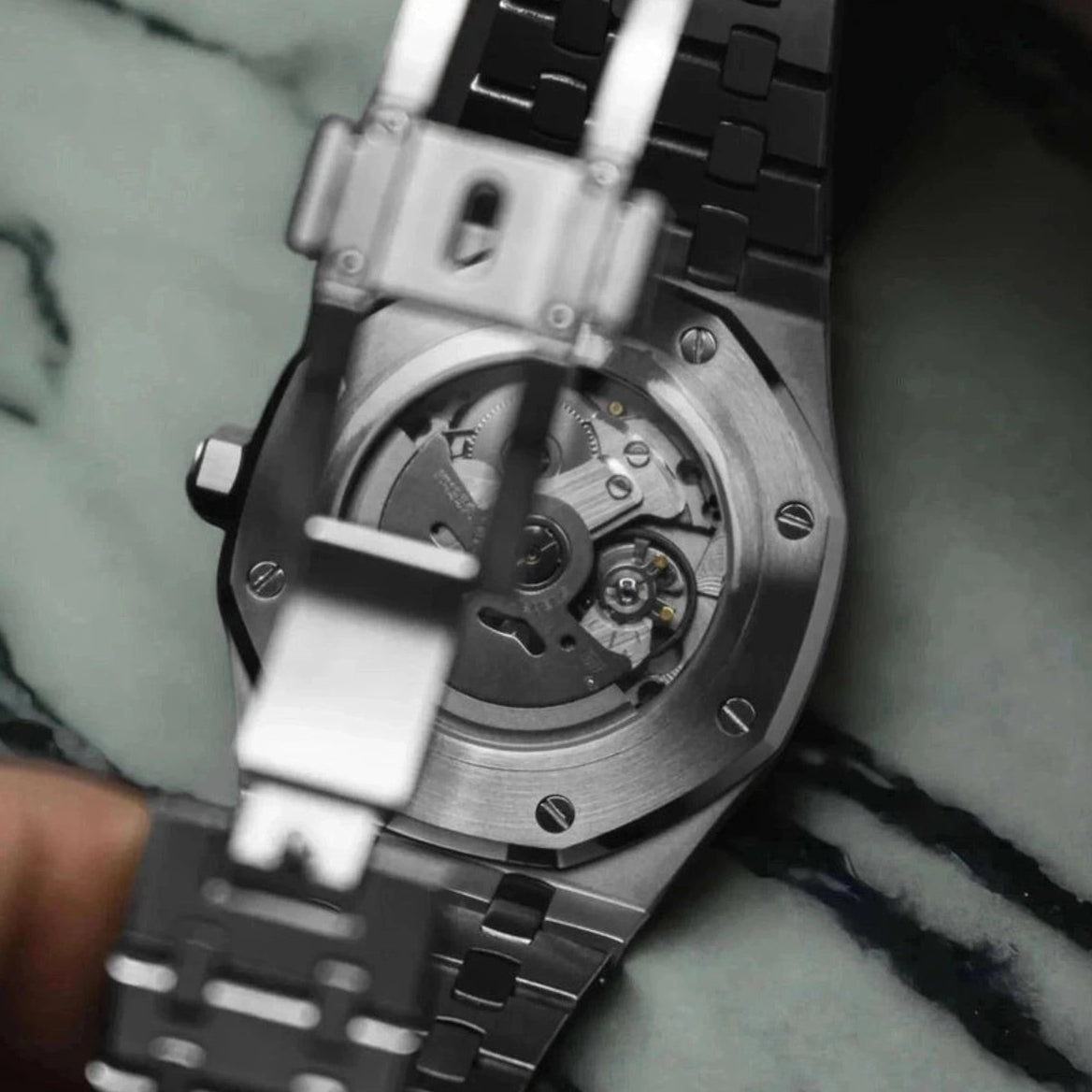 Close-up of a silver watch with a visible brand logo on a marble surface
