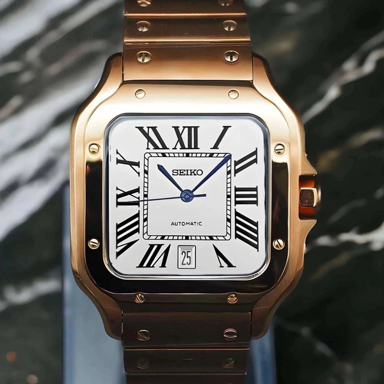 Rose gold Seiko watch with a white face and black Roman numerals on a reflective surface.
