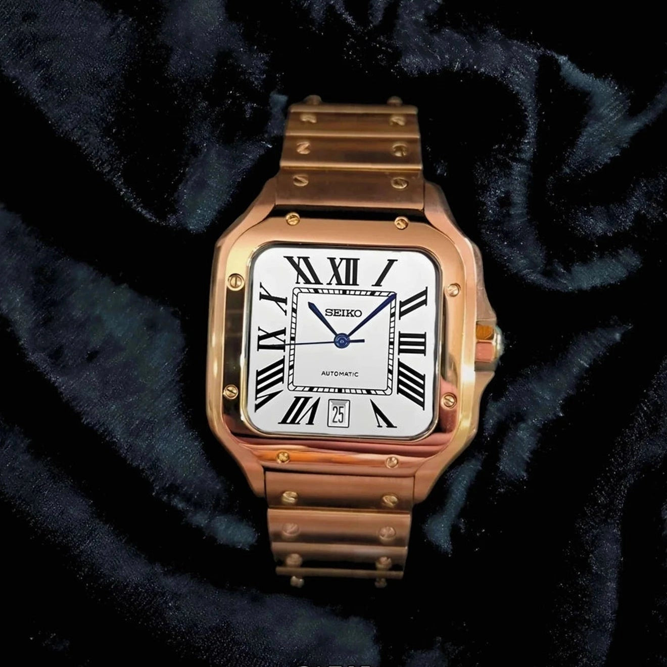 Rose gold watch with white face and Roman numerals on a dark fabric background, featuring the brand 'CW'.