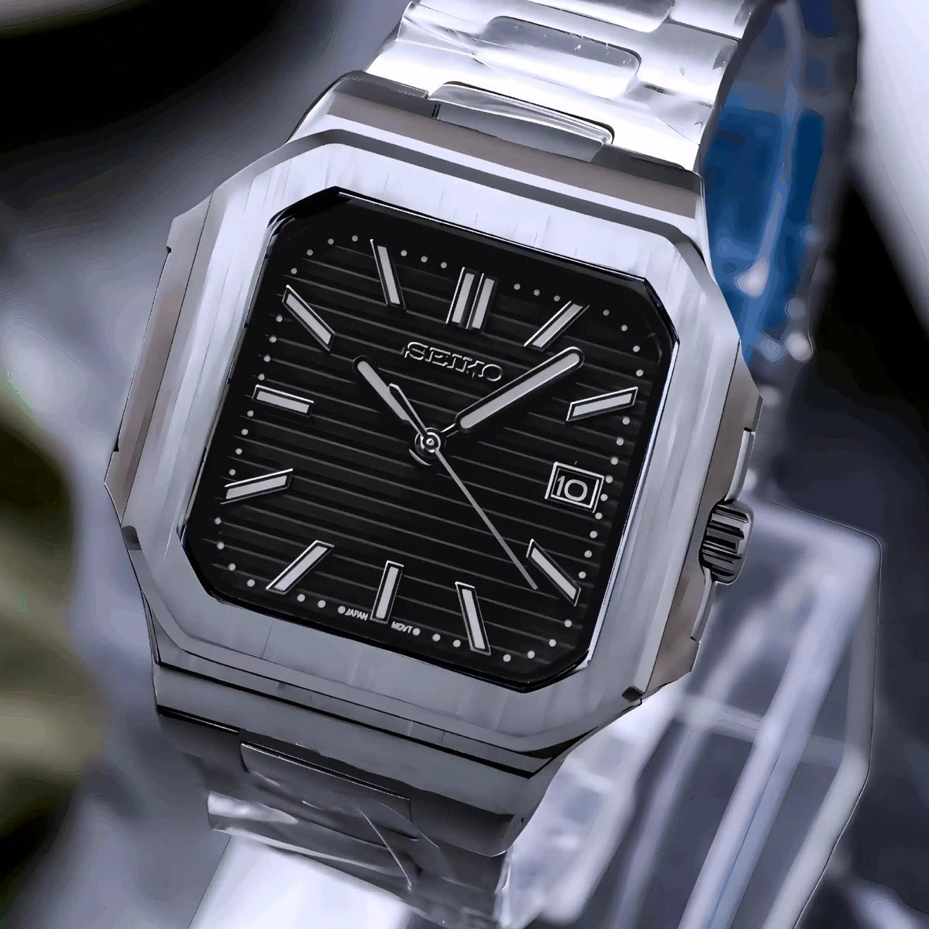 Silver watch with black face on a stand