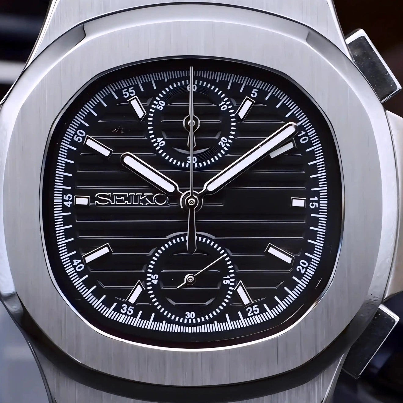 Silver Seiko watch with black face on a dark background