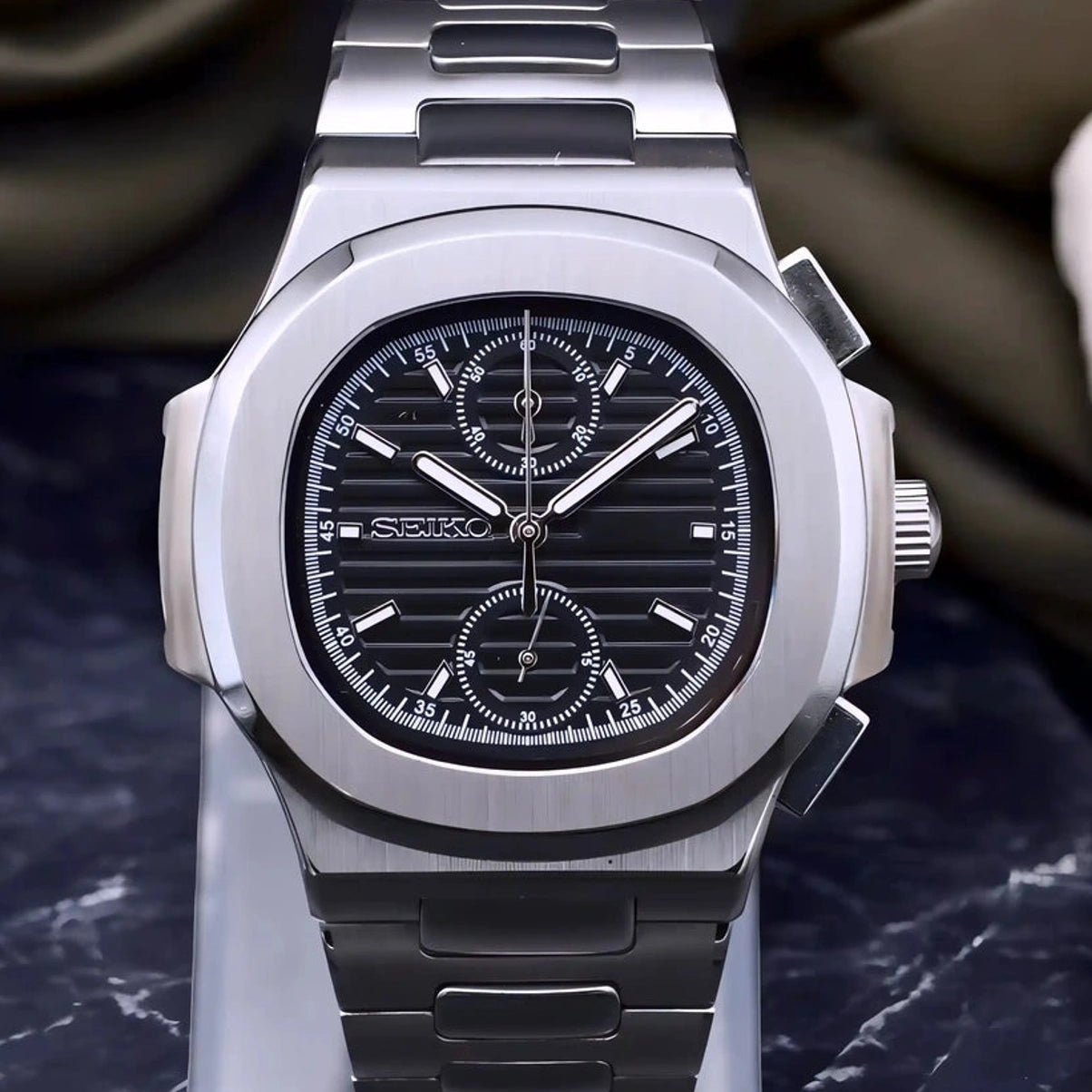 Luxury seikonautilus chronograph watch on a stand with a blurred background