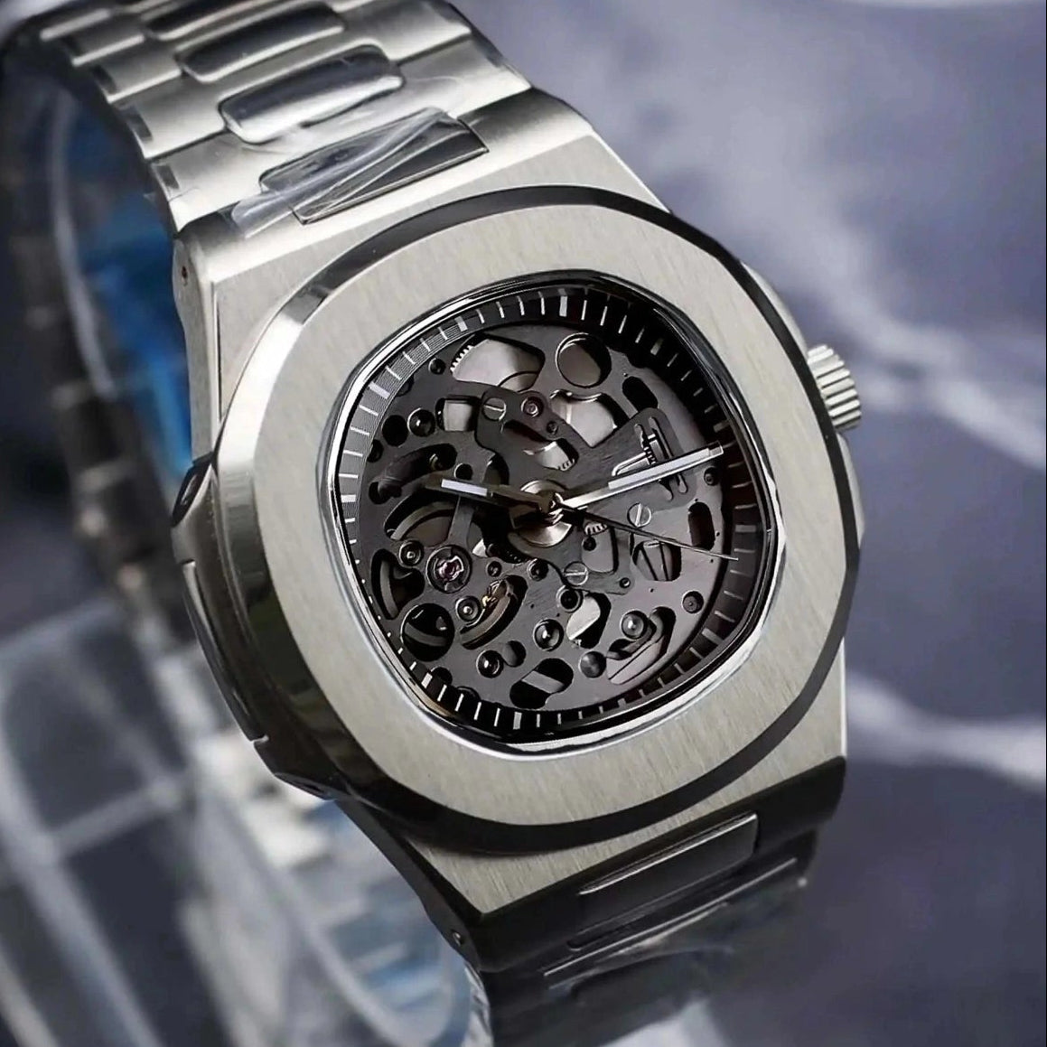 Silver watch with a clear stand on a dark marble surface