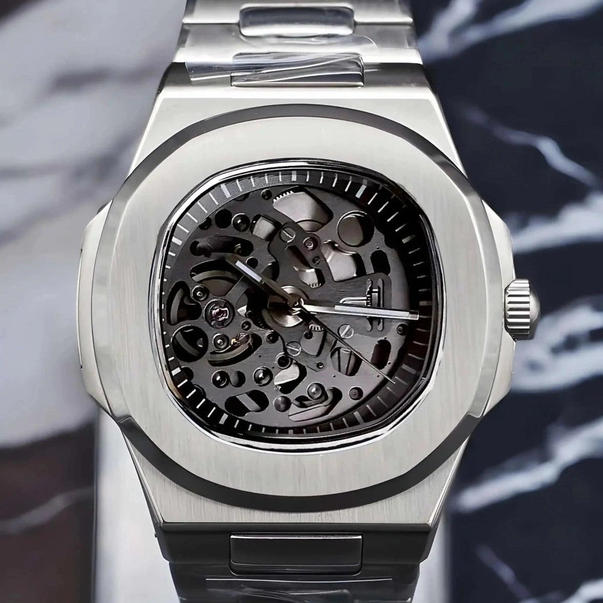 Silver skeleton watch with visible brand logo on a marble surface