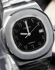 Silver and black watch with arabic hour indicies on a stand