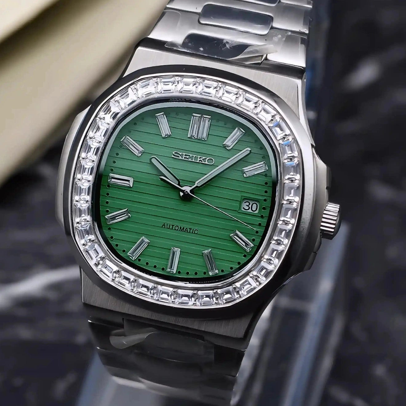 Silver watch with green face on a dark textured background