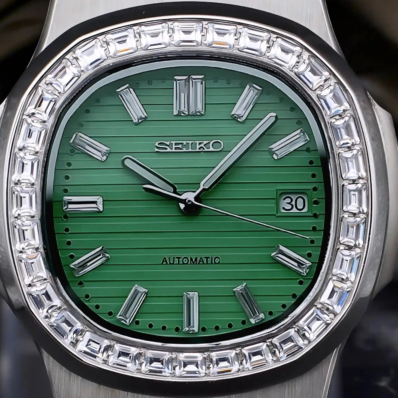 Silver Seiko watch with green face and diamond bezel on a dark background