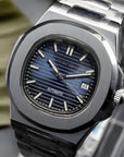 Luxury watch with blue dial and black strap on a stand