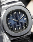Silver watch with blue face on a reflective surface